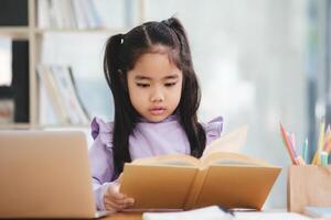 une Jeune fille est séance à une bureau en train de lire une livre photo