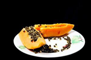 proche en haut vue de Papaye fruit isolé sur assiette sur noir Contexte. photo