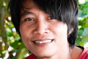 une fermer de le visage de une Javanais homme qui apparaît à avoir longue cheveux. photo