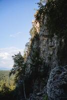 une Montagne intervalle dans le forêt, une Roche illuminé par le soleil, une paysage de touristique attractions, une protégé itinéraire, le pierre des murs de le Montagne. photo