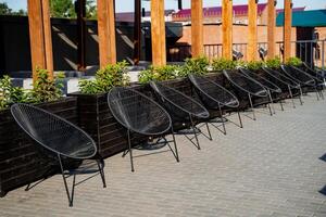 Extérieur café chaises pour relaxant dans le soleil, une restaurant sur le trottoir dans le ville, le intérieur de le des loisirs facilité, noir osier chaises. photo