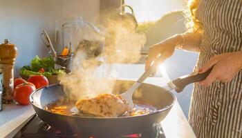 une la personne est cuisine poulet dans une la poêle sur une le fourneau photo