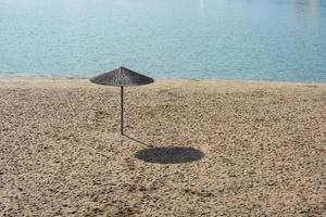 un parapluie de roseau sur une plage vide à midi. photo