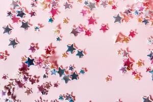 multicolore holographique étoiles briller confettis sur rose Contexte. de fête toile de fond, sélectif concentrer photo