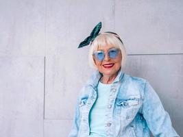 femme élégante senior aux cheveux gris avec bandeau à la mode et lunettes bleues. mode, anti-âge, détente, vacances, concept de retraite photo