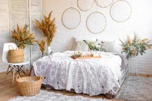 bel intérieur de maison aux tons blancs et beiges, avec des capteurs de rêves, des fleurs séchées et un lit photo