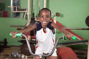 petit garçon souriant sur un vélo d'entraînement dans une salle de sport. photo