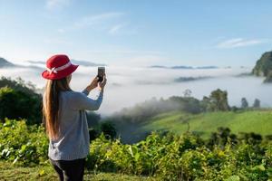 voyageur femme portant un chapeau à l'aide d'un téléphone intelligent prendre une belle montagne photo