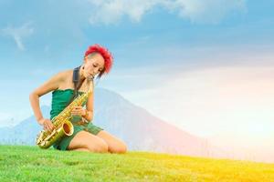 jeune femme saxophoniste aux cheveux rouges jouant du saxophone dans la nature montagnarde. photo