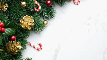 feuilles de pin vert, décorations de noël rouges et cannes de bonbon sur fond de marbre blanc, décorations de noël de couleur rouge vif. concept de noël simple et créatif. photo