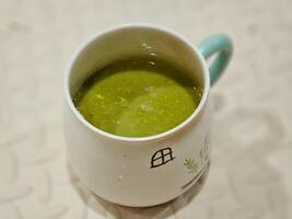 proche en haut de une tasse de Avocat jus sur beige bois et flou Contexte photo