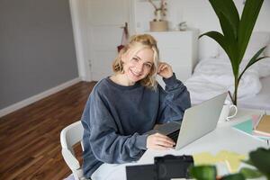 portrait de Jeune femme, mode de vie blogueur, enregistrement vlog à propos sa la vie et du quotidien routine, séance dans de face de ordinateur portable, parlant à suiveurs, séance dans sa pièce photo