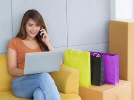 femme d'affaires est commerce électronique entrepreneur séance à le chaise parlant sur téléphone intelligent et allonger le portable sur sa jambe dans sa bureau. Jeune femme une négociation à propos entreprise. affaires concept photo