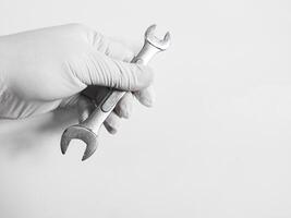 homme main avec gants détient une clé outils isolé sur blanc Contexte. photo