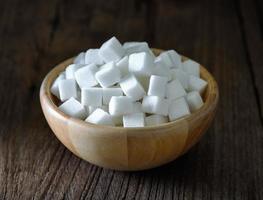 cubes de sucre dans un bol en bois sur une table en bois photo