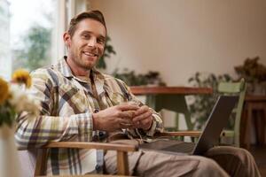 Beau Jeune professionnel, homme d'affaire séance dans café avec verre de café et travail sur ordinateur portable, recherche pour inspiration à l'extérieur de Bureau espace de travail photo