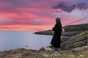 solitaire et triste fille en train de regarder le coucher du soleil par le mer. désir pour le distance et le passé. photo
