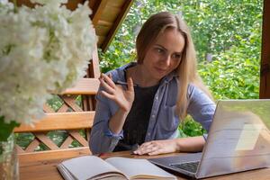 Jeune content femme se concentre sur sa portable dans en bois alcôve. détendu Extérieur réglage souligne confort et productivité. éloigné travail apprentissage concept photo