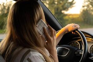 Jeune femme en utilisant mobile téléphone tandis que conduite voiture sur Autoroute route pendant le coucher du soleil. femmechauffeur a accident appel avec téléphone intelligent pour aider. affaires femme occupé conduite concept photo