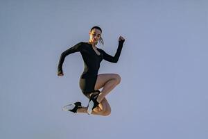 souriant sportif femme dans tenue de sport sauter sur studio Contexte. sport et en bonne santé mode de vie photo