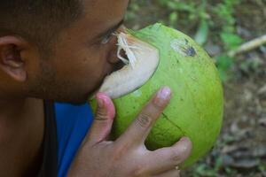 tasik malaya, ts, 2023 - une Javanais homme les boissons vert noix de coco l'eau dans une village dans tasik malaya, Ouest Java photo