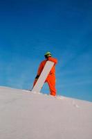 snowboarder freerider avec snowboard blanc debout au sommet de la piste de ski photo