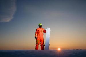 snowboarder au sommet de la piste de ski au fond d'un beau coucher de soleil photo