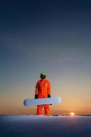 snowboarder au sommet de la piste de ski au fond d'un beau coucher de soleil photo