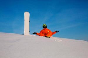 snowboarder freerider avec snowboard blanc assis au sommet de la piste de ski photo