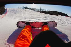 Point de vue tourné d'un snowboarder masculin assis sur la neige photo