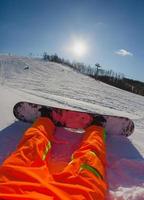 Point de vue tourné d'un snowboarder masculin assis sur la neige photo