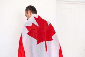 Jeune homme en portant Canada drapeau dans blanc arrière-plan, drapeau de Canada. photo