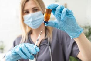 biologique danger. épidémie de le chinois corona virus. un femme dans une protecteur masque détient un injection seringue et vaccin. vaccin grippe, corona virus, Ebola, tb. photo