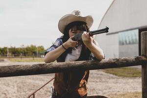 portrait de une magnifique chinois femelle cow-girl tournage avec une arme photo