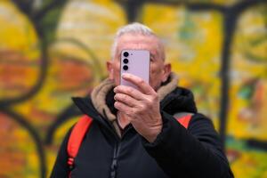 content milieu vieilli homme sur vacances prise une selfie dans de face de défocalisé graffiti dans Rome photo