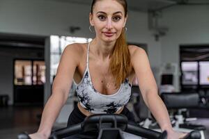 Jeune mignonne femme dans serré des sports costume formation sur exercice bicyclette dans Gym photo