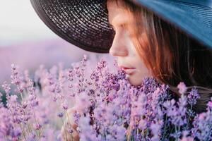 femme lavande champ. content insouciant femme dans noir robe et chapeau avec grand bord odeur une épanouissement lavande sur le coucher du soleil. parfait pour inspirant et chaud concepts dans Voyage et esprit d'aventure. proche en haut photo