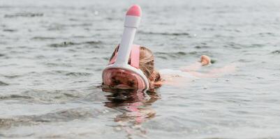 Jeune content femme dans blanc bikini et portant rose masque obtient prêt pour mer plongée en apnée. positif souriant femme relaxant et profiter l'eau Activités avec famille été Voyage vacances vacances sur mer. photo
