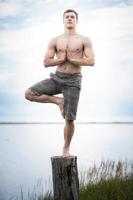 Jeune adulte faisant du yoga sur une souche dans la nature photo