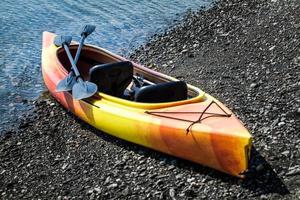 kayak orange et jaune avec des rames au bord de la mer