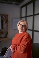 portrait de une femme avec une invalidité dans un Orange chandail et cuir un pantalon dans le Bureau photo