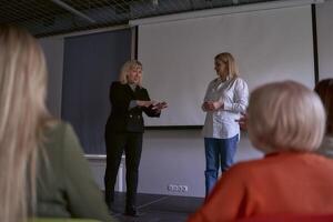 deux milieu âge femmes dans affaires costume sur étape dans le Bureau photo