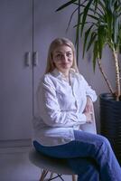 portrait de une blond femme dans jeans et une blanc chemise dans le Bureau photo