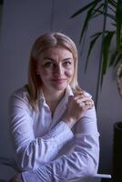 portrait de une blond femme dans jeans et une blanc chemise dans le Bureau photo