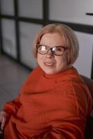 portrait de une femme avec une invalidité dans un Orange chandail et cuir un pantalon dans le Bureau photo