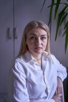 portrait de une blond femme dans jeans et une blanc chemise dans le Bureau photo