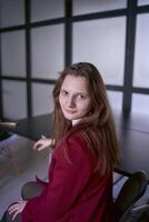 portrait de une Jeune femme dans une rouge Bureau costume photo