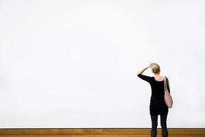 femme s'interrogeant devant un mur blanc photo