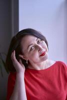 portrait de une brunette avec une bob la Coupe de cheveux dans une rouge chandail et une cuir mini jupe dans le Bureau photo