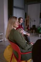 femmes regarder leur collègues parler sur organiser, séance sur chaises et haricot sac photo